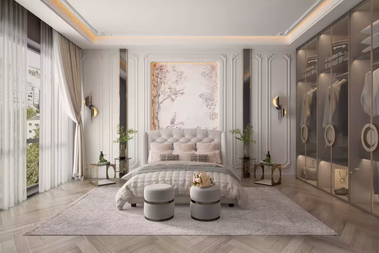 Luxury contemporary bedroom with white decorative wall paneling and gold vertical insets, a large tufted dove-grey wingback headboard, floral art panel above the bed, twin round ottomans at the foot, gold wall sconces, and a mirrored wardrobe on the right