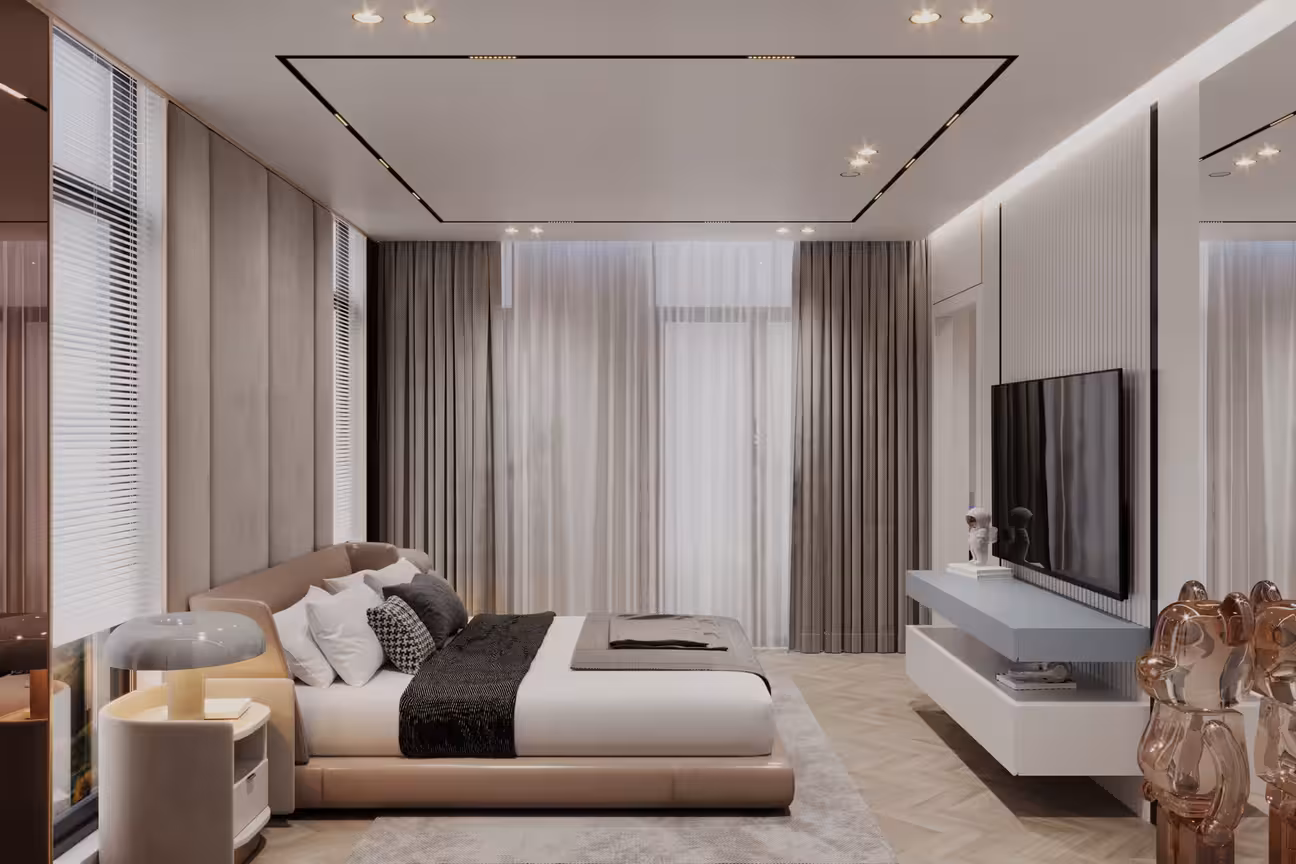 Apartment bedroom with a contemporary floating white TV wall unit on the right, low upholstered bed with layered white and charcoal bedding, floor-to-ceiling layered grey curtains, recessed ceiling frame lighting, rose gold sculptural accent on the bedside, and herringbone parquet floor