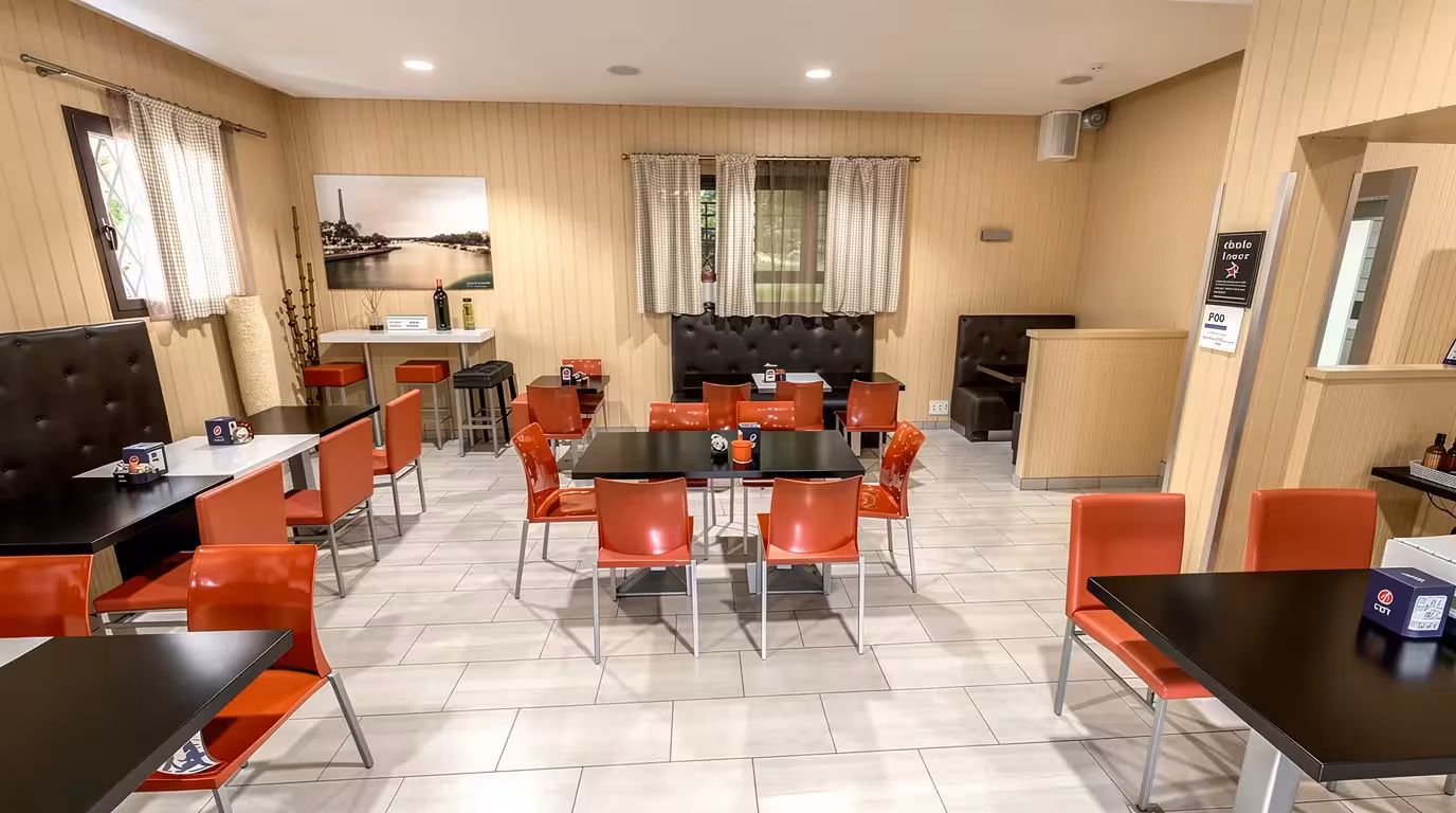 Contemporary cafe interior with red dining chairs, black tables, booth seating, and warm wood wall paneling