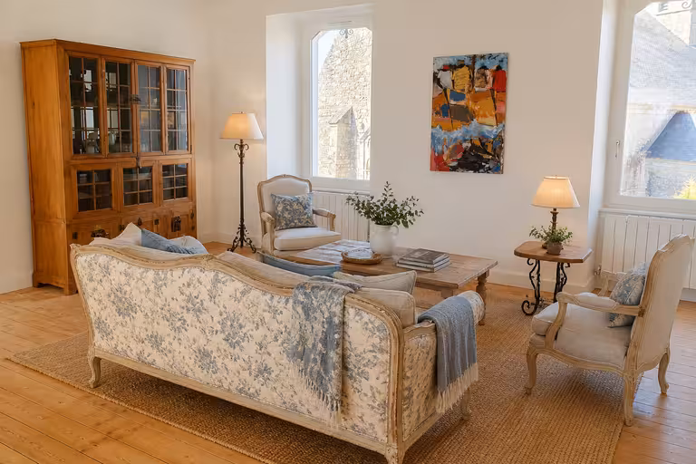 French country living room with floral sofa, classic armchairs, natural wood furniture, and warm neutral decor