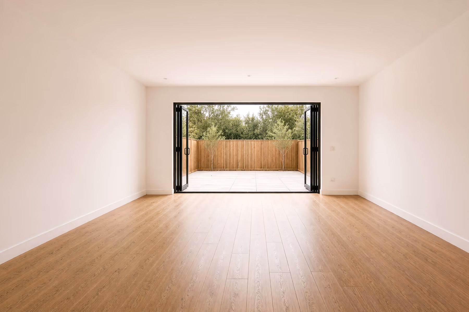 Empty open plan home interior with oak flooring and bifold doors before an AI redesign