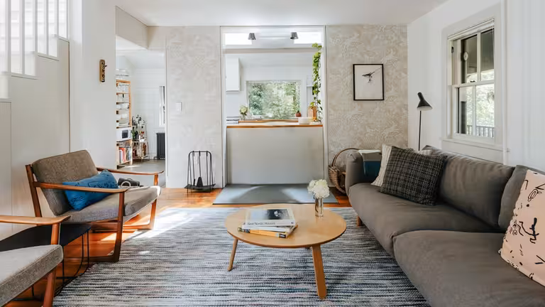 Scandinavian living room with neutral tones, wooden furniture, gray sofa, patterned rug, minimalist decor, natural light