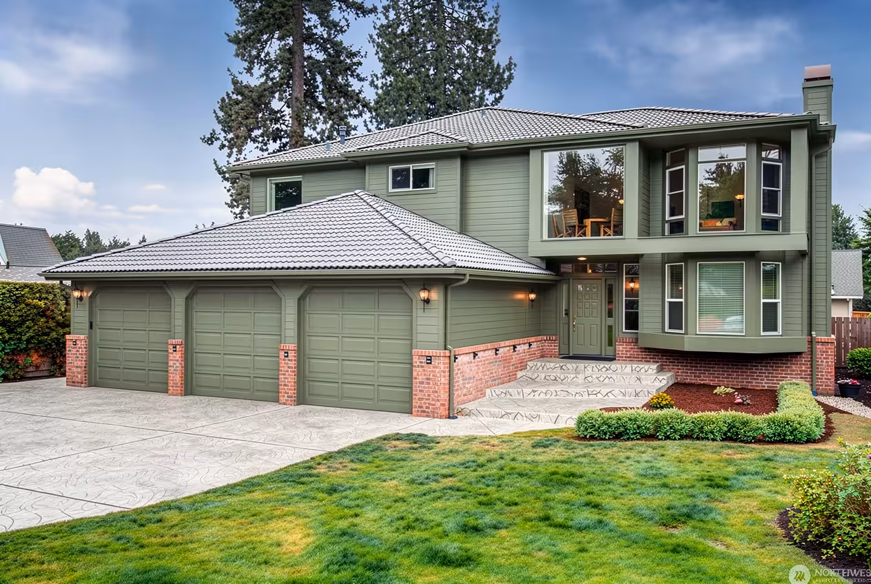 Contemporary house exterior with greenish gray siding, stamped concrete steps, expanded windows, and landscaped front yard