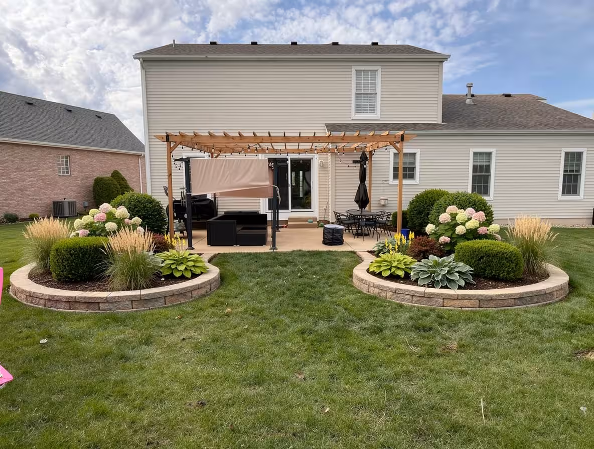 Midwestern backyard with raised stone garden beds, pergola patio, hydrangeas, and manicured landscaping