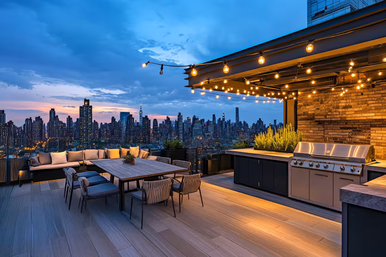 Rooftop restaurant outdoor kitchen with grill station, dining table, lounge seating, and city skyline view in evening setting