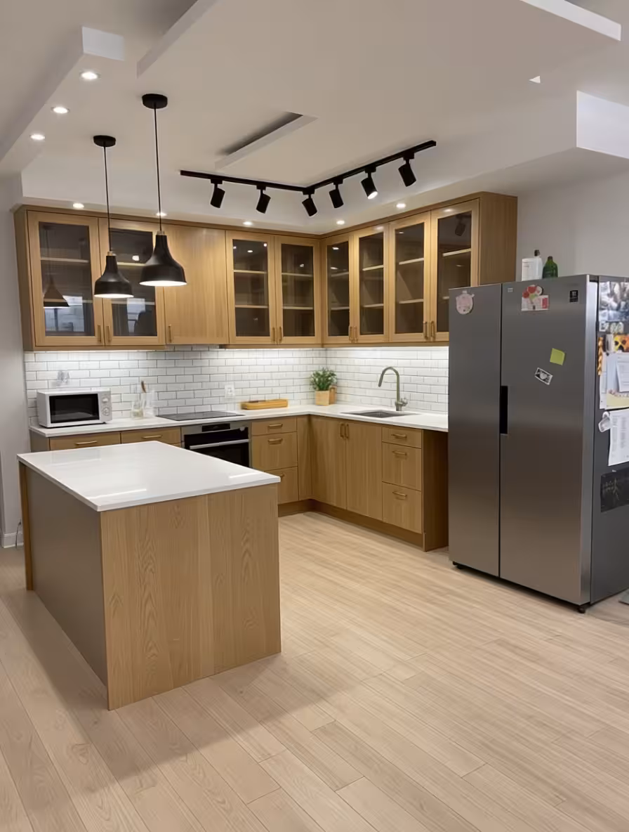 Modern Scandinavian kitchen with light wood cabinets, white subway tile backsplash, black pendant lights, and central island countertop