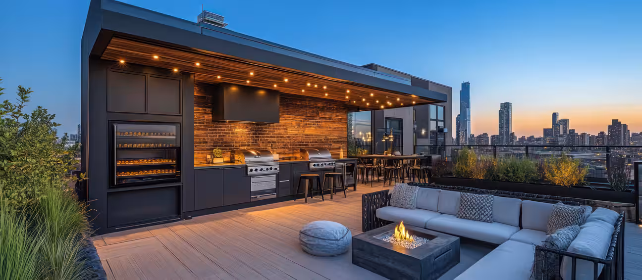 Modern rooftop outdoor kitchen with fireplace, bar seating, and city skyline view, designed for elevated patio dining and evening gatherings