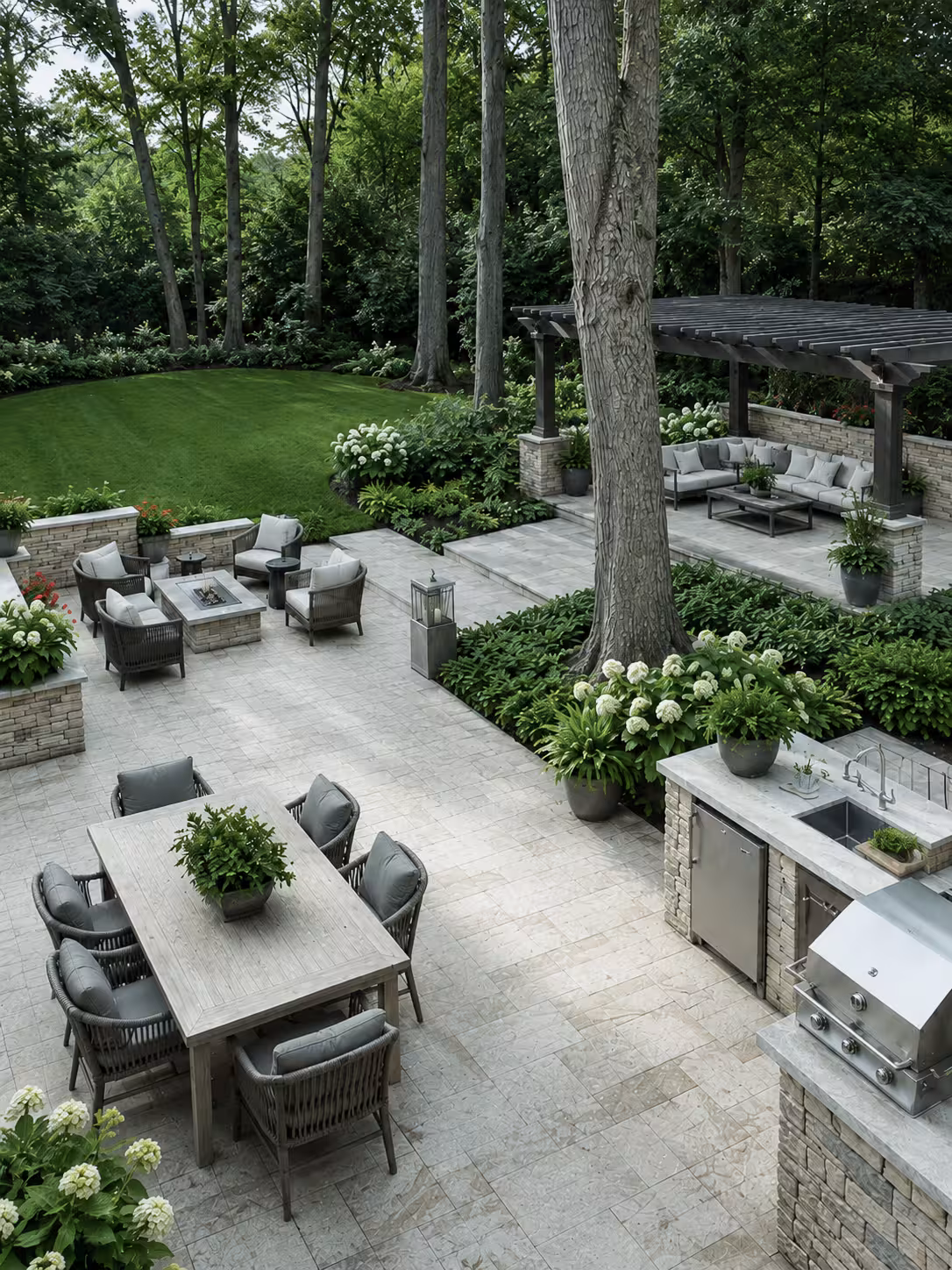 Luxury backyard with five zones including outdoor kitchen, dining table, fire pit lounge, shaded pergola sectional, and lawn leading to woodland
