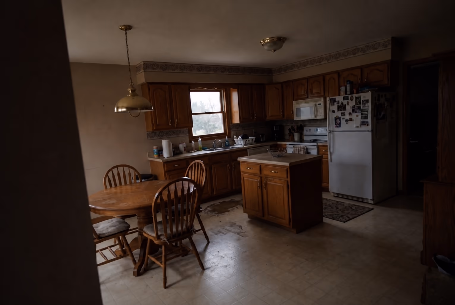 A wider photo of the same dated kitchen showing more of the room from the doorway