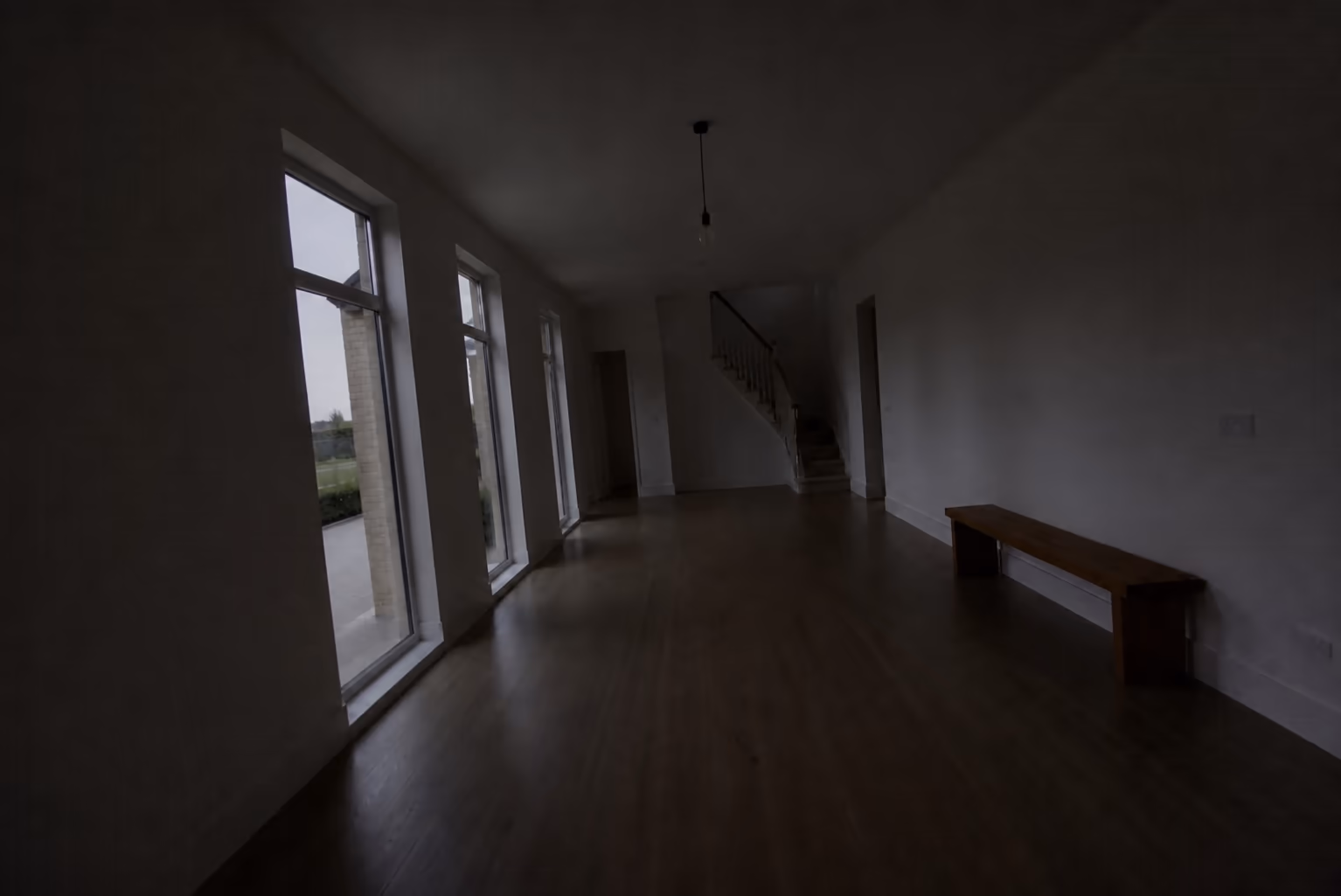A dim, underexposed phone photo of an empty entrance hall with the lights off