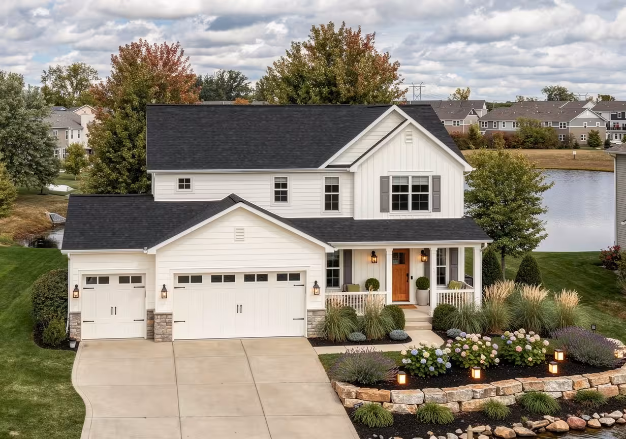Modern farmhouse house exterior with white siding, stone accents, warm landscaping, and black roof