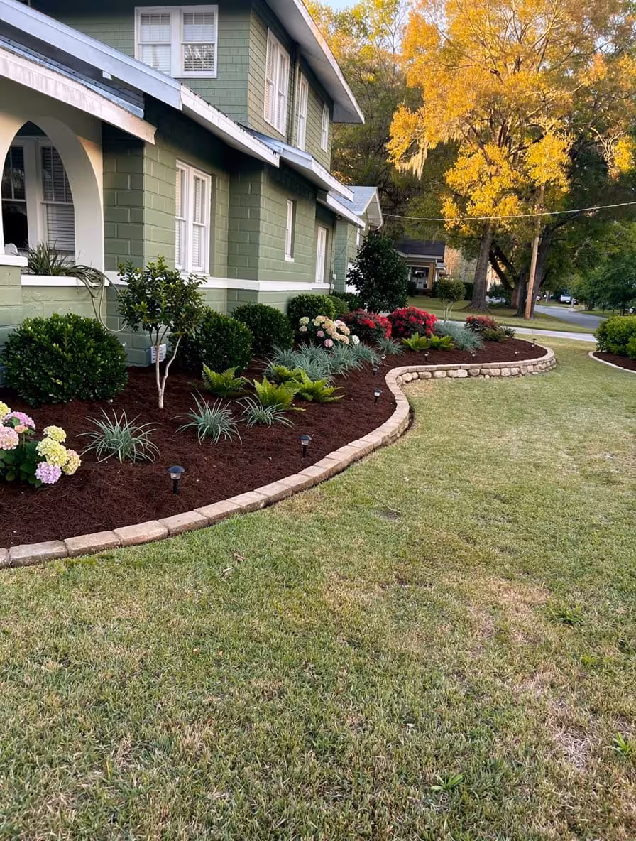 Southern Craftsman front yard with curved mulch beds, flowering shrubs, ornamental grasses, and foundation landscaping