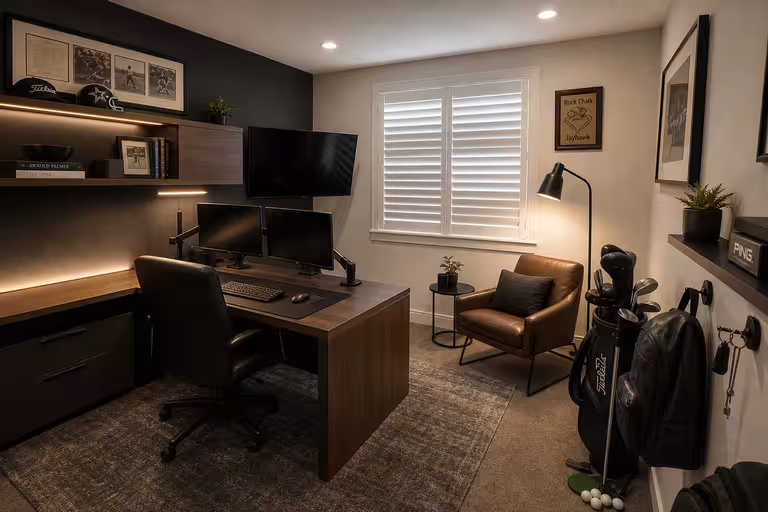 Modern minimalist home office with walnut desk, warm lighting, and masculine lounge styling