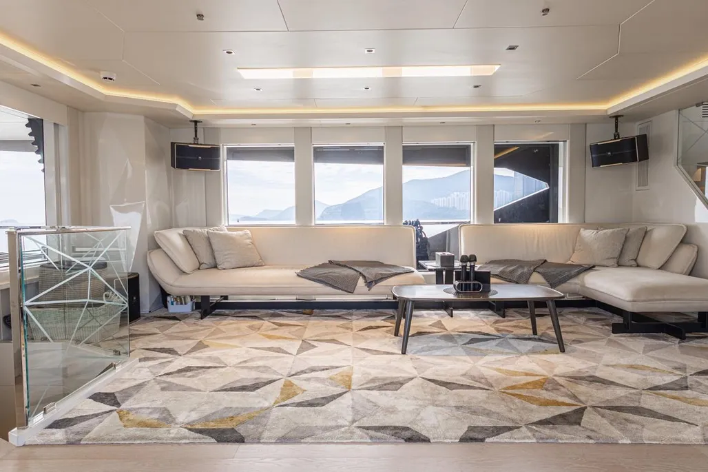 Living room with sectional sofa, geometric area rug, recessed lighting, and large windows