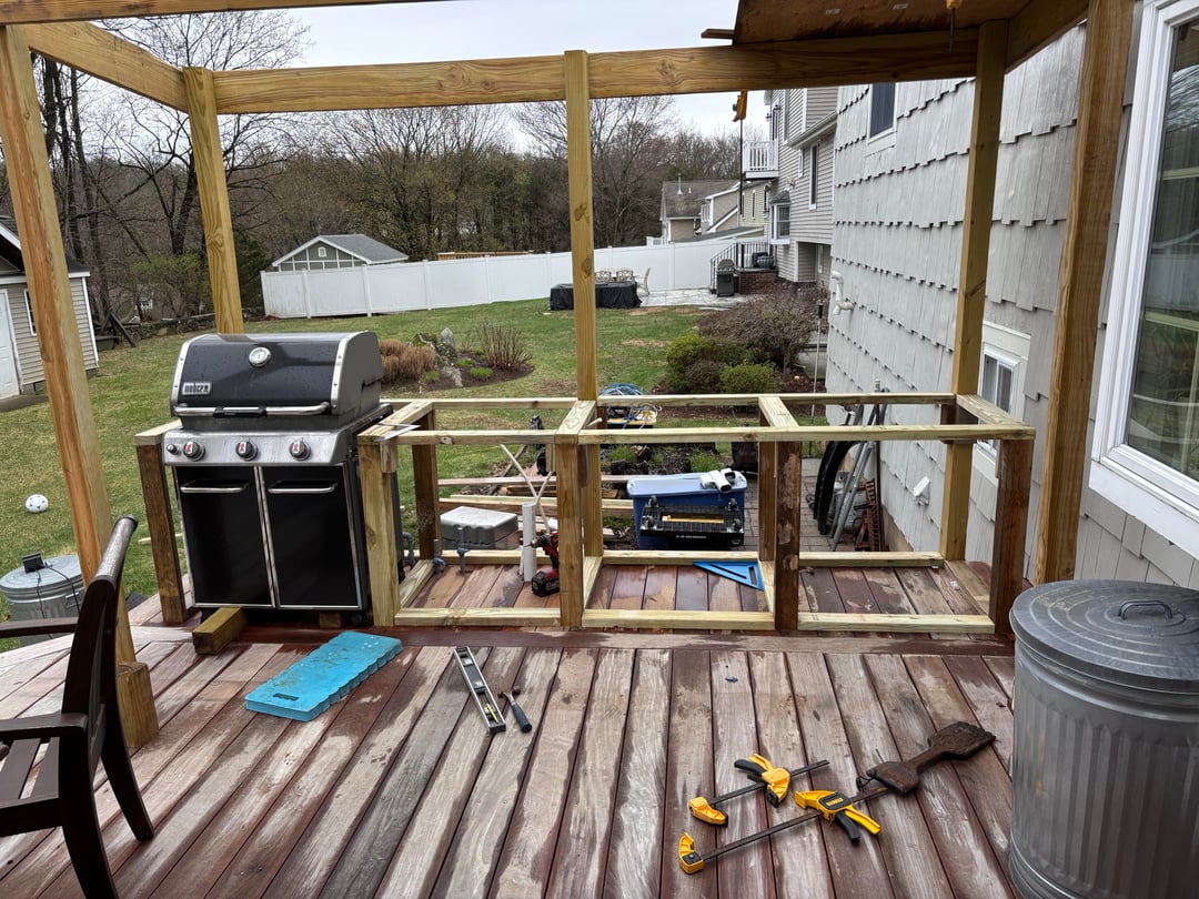 Unfinished covered deck kitchen with exposed framing and outdoor grill