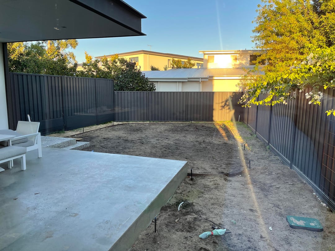 Bare backyard with dirt ground, black fencing, and unfinished landscaping