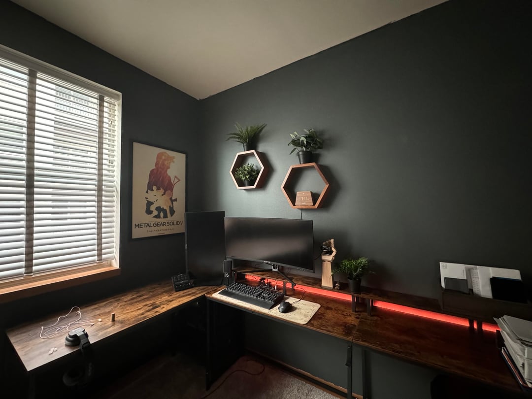 Dark modern home office with gaming desk setup and black accent wall