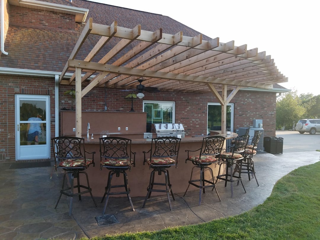 Basic covered outdoor kitchen with unfinished pergola and metal bar stools