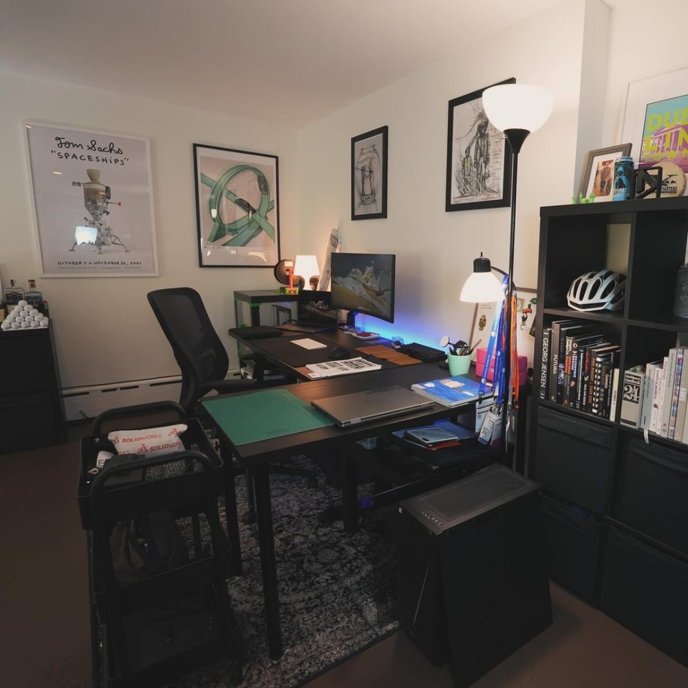 Home office with dark desk, shelving unit, and framed wall art