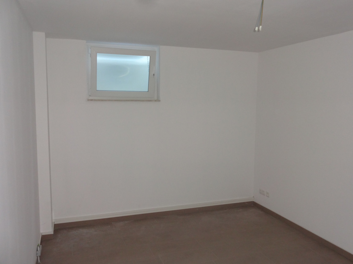 Empty room with white walls, gray flooring, and small frosted window