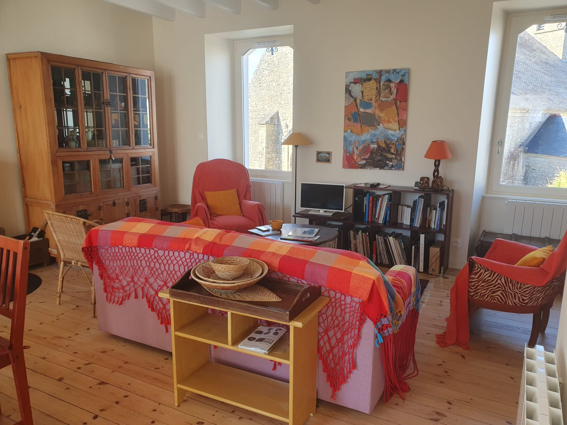 Living room with colorful textiles, wooden cabinet, armchairs, and natural wood flooring