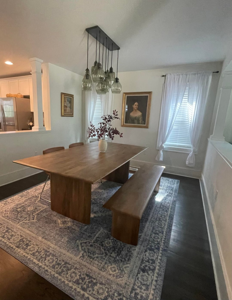 Dining room with dark wood table, bench seating, glass pendant lights, and framed portrait artwork