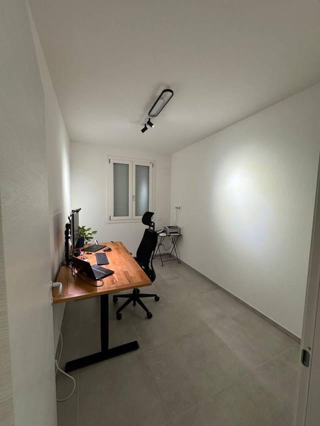 Narrow home office with simple desk setup and white walls