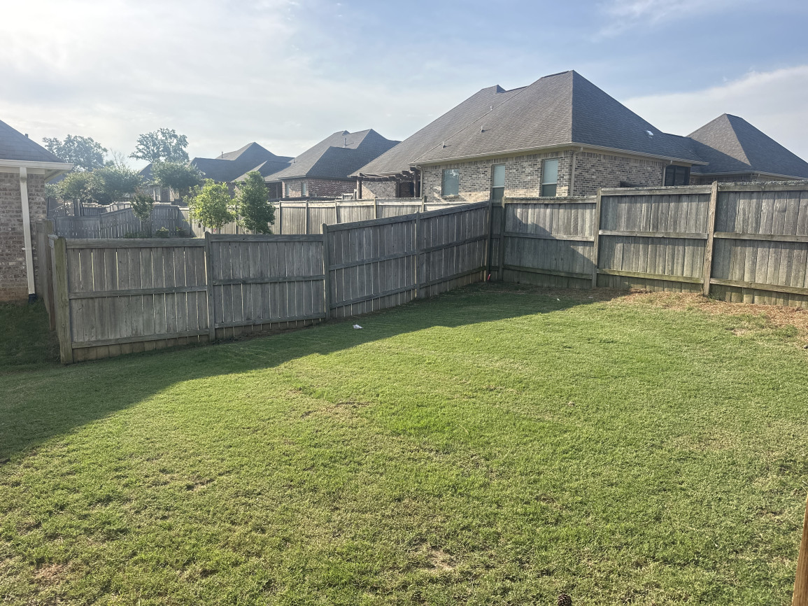 Empty fenced backyard with open grass lawn and no landscaping