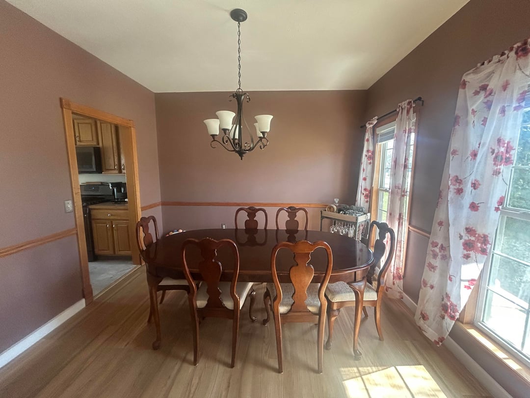 Dining room with dark wood table, floral curtains, mauve walls, and traditional chandelier lighting
