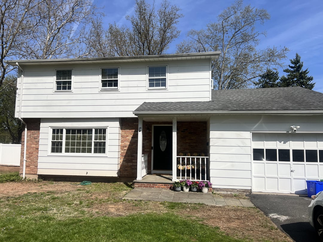 Traditional white two-story suburban house exterior with brick accents and attached garage