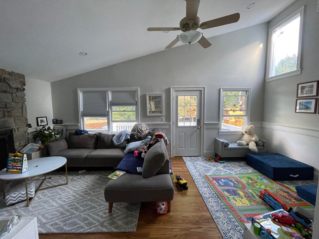 Open concept family living room with sectional sofa, colorful kids rug, vaulted ceiling, and toy play area.
