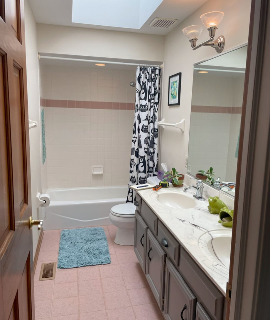 Bathroom with pink floor tiles, double sink vanity, bathtub shower combo, and patterned shower curtain