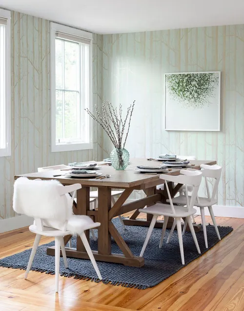 Dining room with wood table, white chairs, light wallpaper, and minimal modern decor.