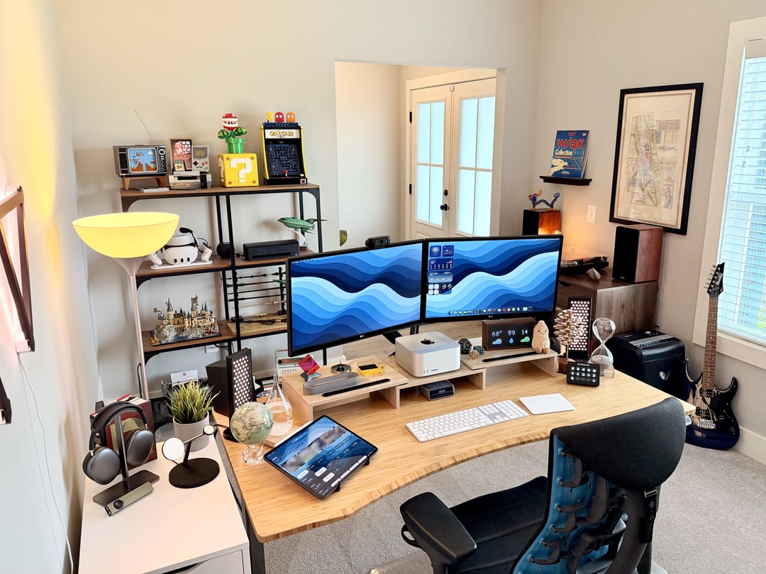 Home office with dual monitors, shelving unit, and light wood desk setup