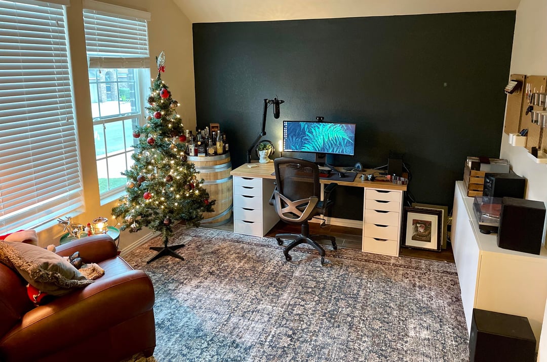 Home office with dark accent wall, desk setup, and large area rug
