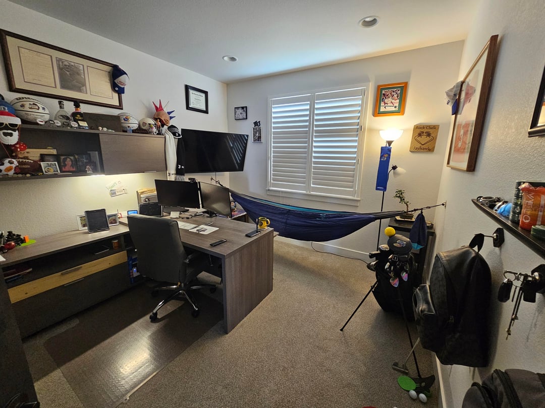 Home office with dark desk setup, sports decor, and golf equipment