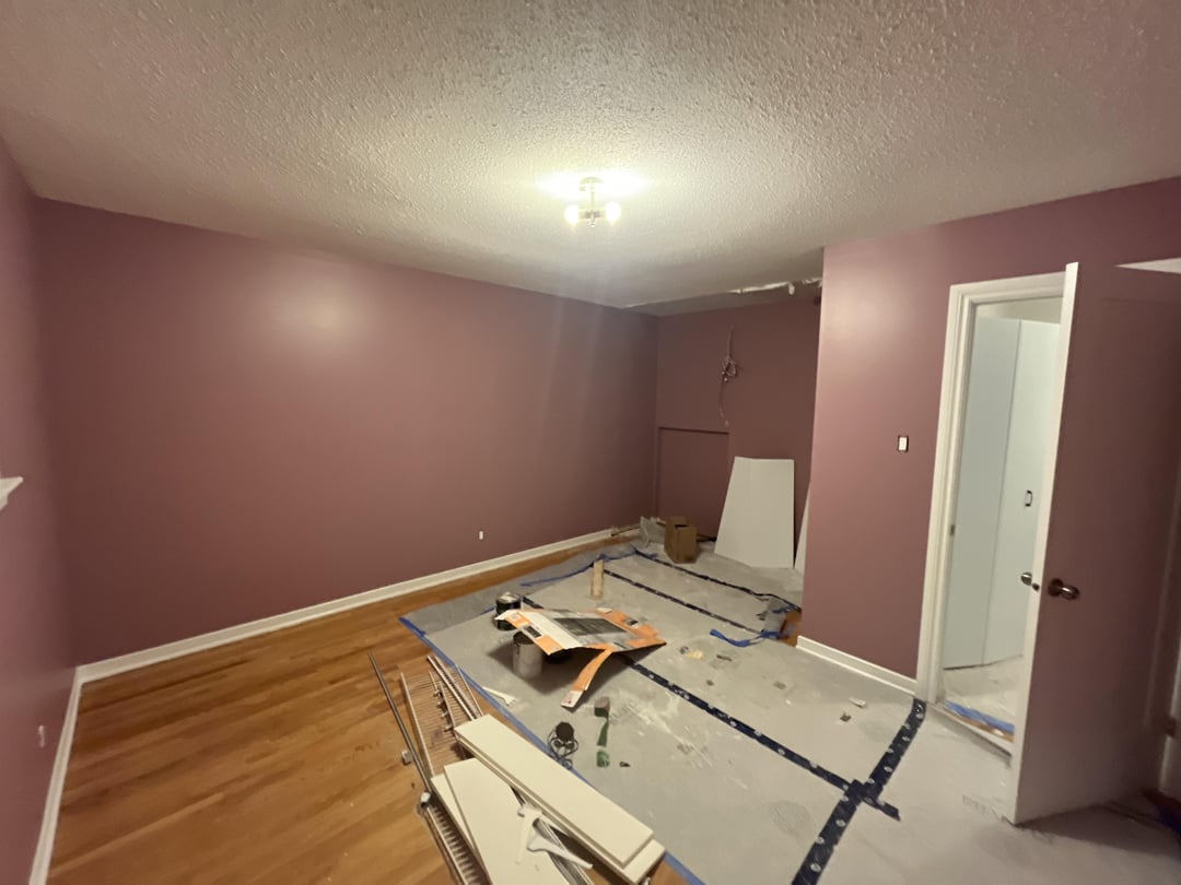 Empty kids bedroom with mauve walls, hardwood flooring, renovation materials, and unfinished open floor space