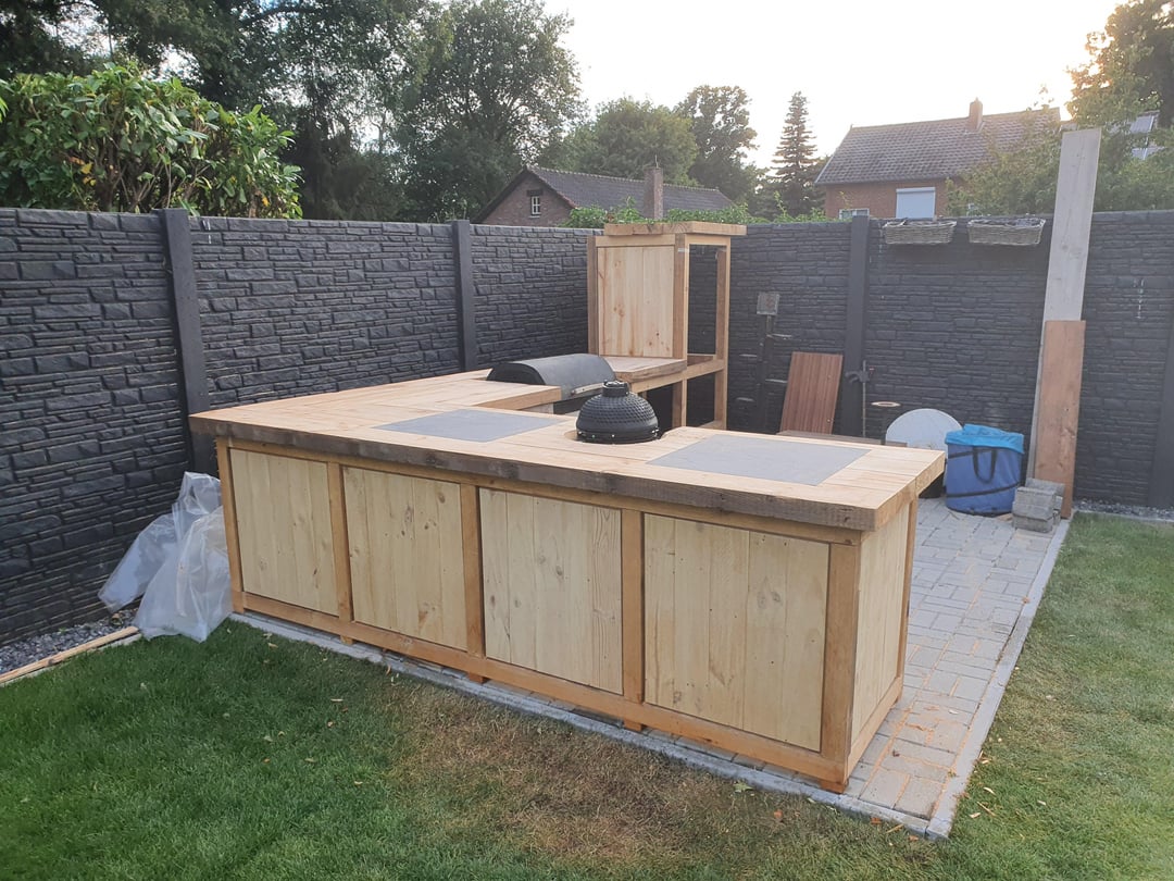Unfinished outdoor kitchen island with raw wood framing and backyard patio