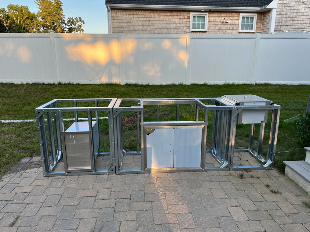 Unfinished outdoor kitchen metal frame structure on backyard patio.