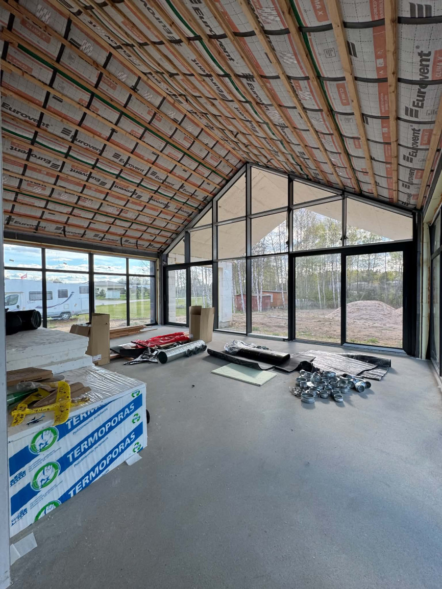 Unfinished interior with exposed insulation, concrete floor, and large floor-to-ceiling windows