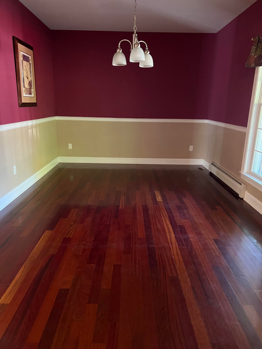 Empty room with burgundy walls, beige wall paneling, dark wood flooring, and white trim molding