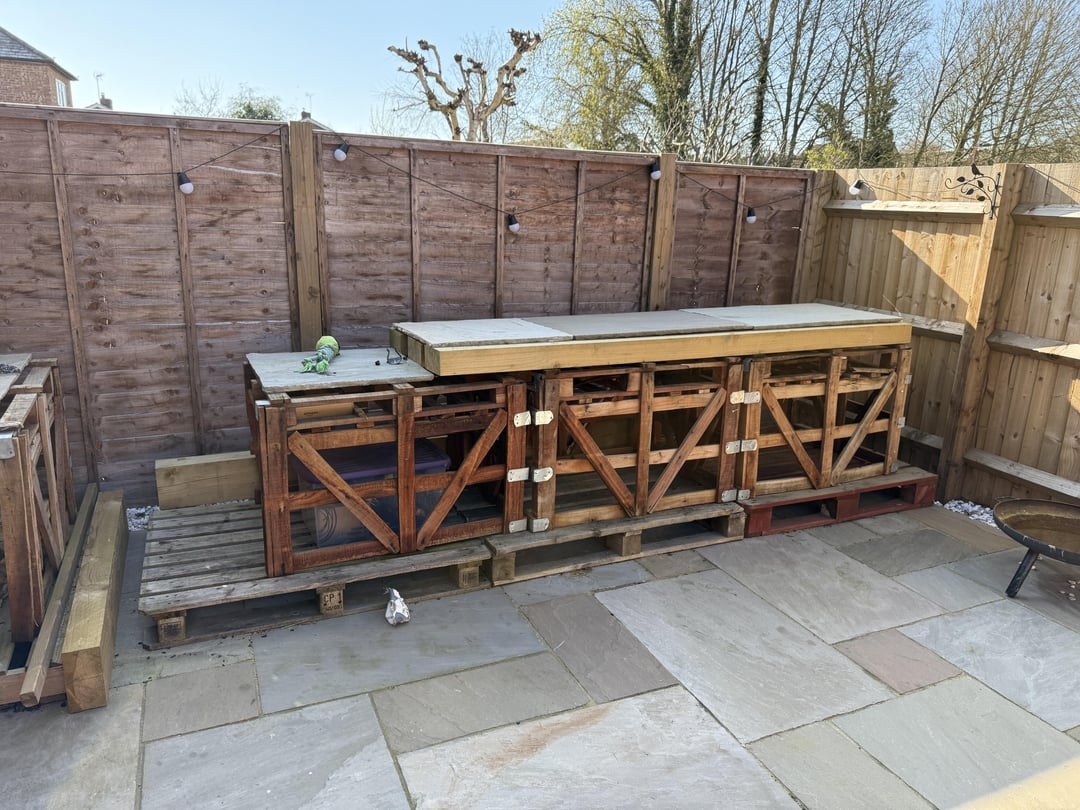 Unfinished outdoor kitchen frame with exposed wood structure and patio flooring.