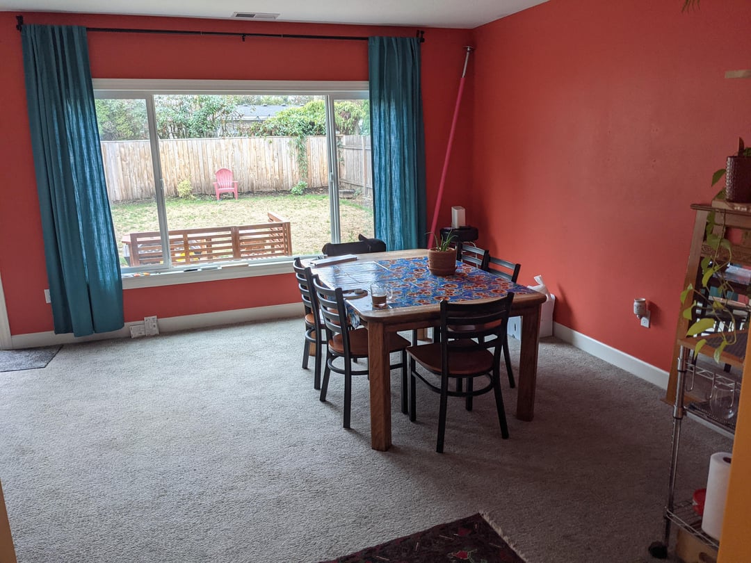 Dining room with red walls, dark wood dining table, blue curtains, and large picture window